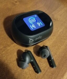 The Poly Voyager Free 60+ UC earbuds outside of the powered-on smart case.